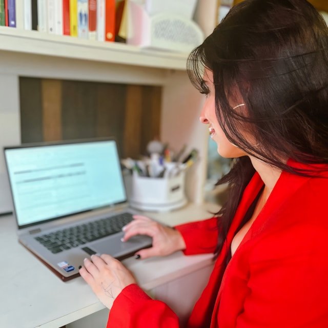 Person browsing content on a laptop screen, representing online research, content writing, and digital workflow Businesswoman using a laptop at a desk, focused on work in a modern home office environment